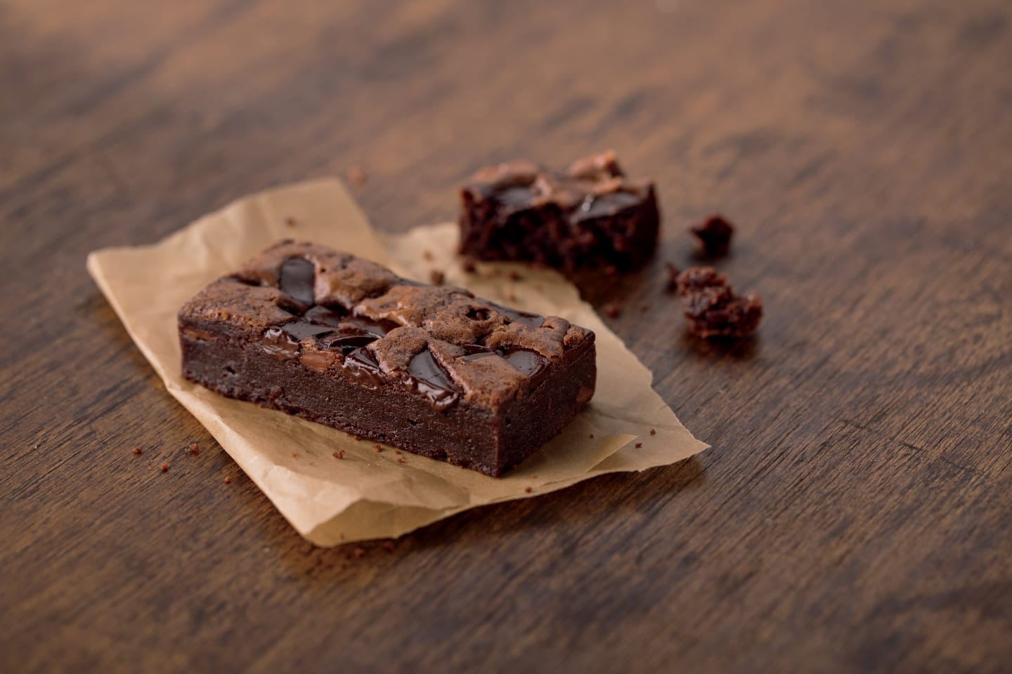 A square of gluten-free fudgy brownie on parchment paper, dark and rich.