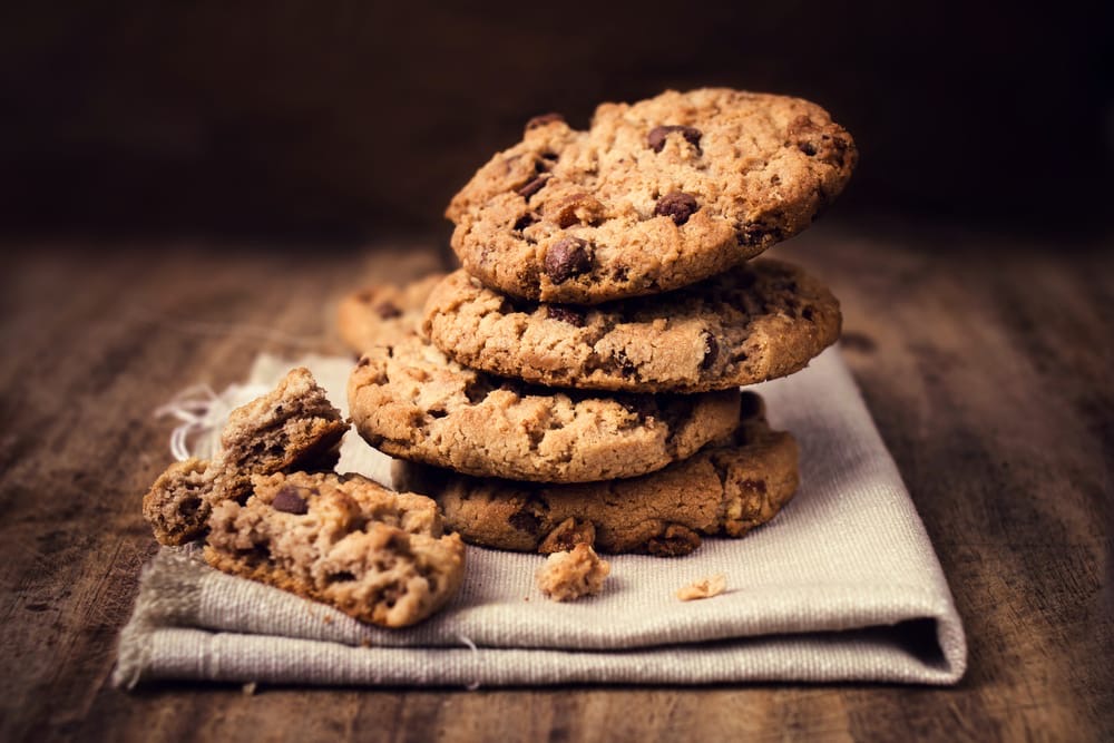 A stack of freshly-baked gluten-free cookies, chewy centre, golden edges.